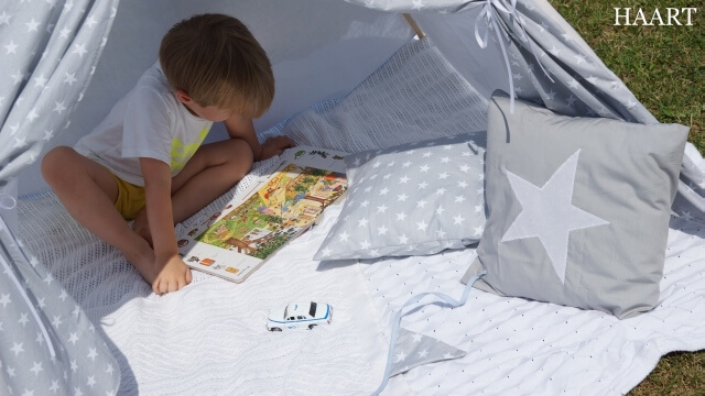 dziecko w namiocie teepee czytające książkę